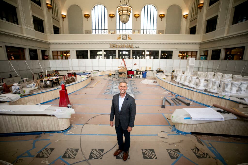 A man in a suit stands in Union Station's towering Great Hall, surrounded by a construction fence and a little bit of chaos as renovations here continue.