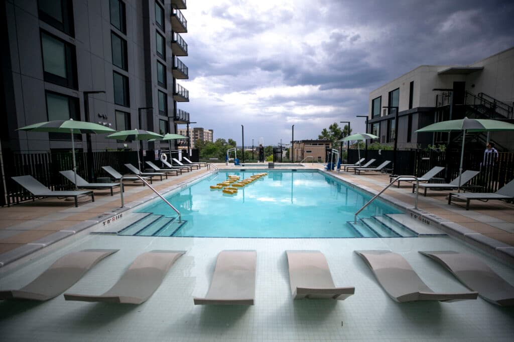 An azure pool beneath a cloudy sky, surrounded by deck chairs and umbrellas.