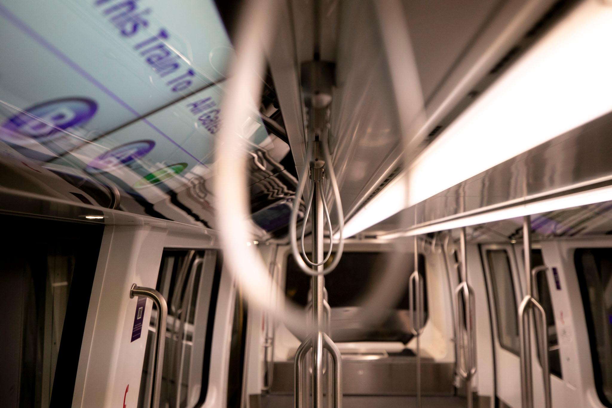 Passenger handles hang from the ceiling of a traincar.