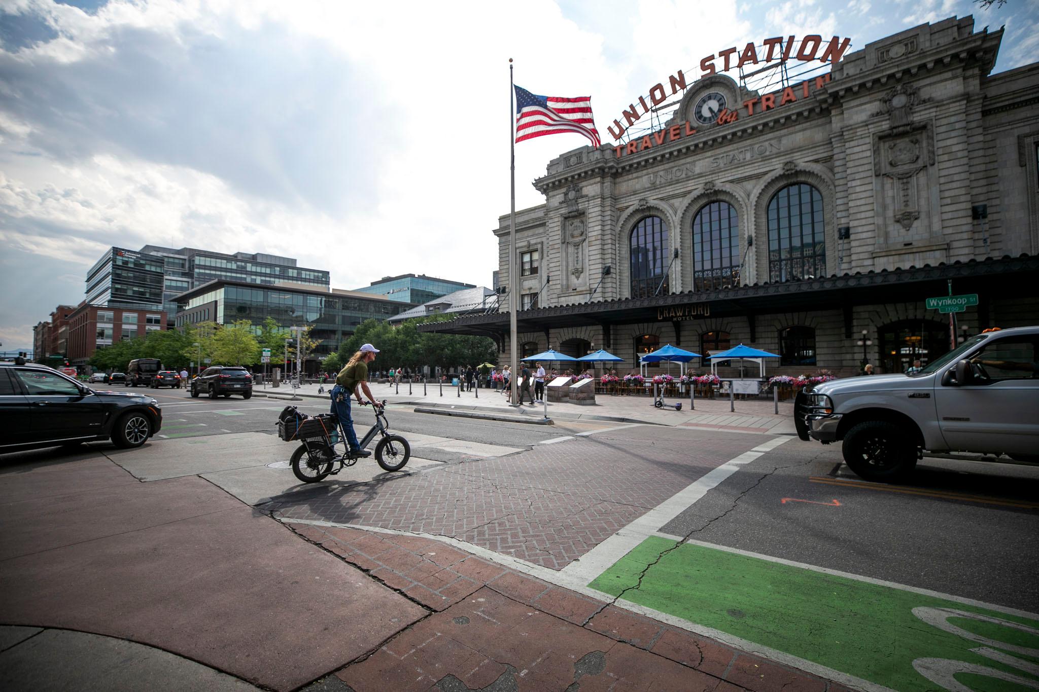 A cyclist crosses a street below Union Station; cars and trucks lurk in the intersection.
