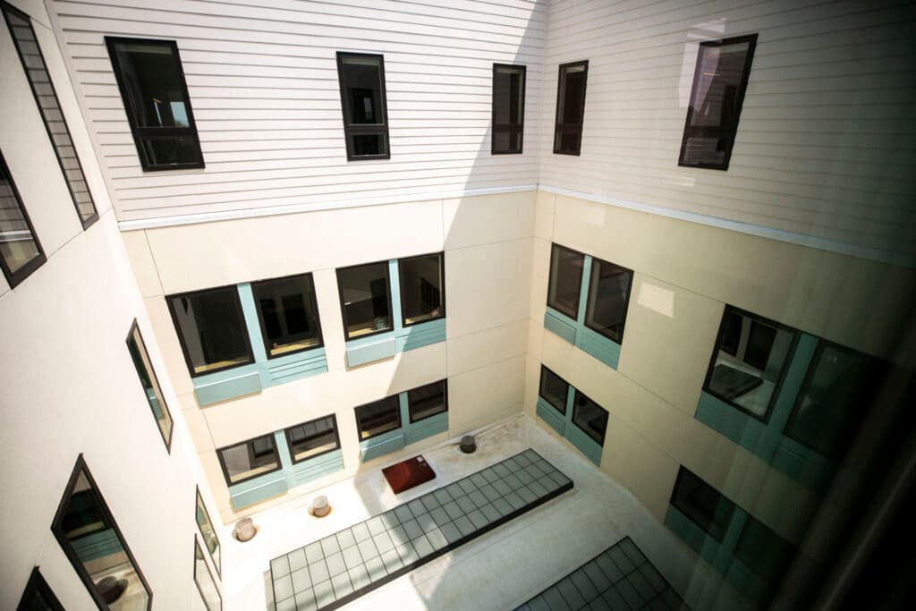 The exterior of a new beige building, punctuated by teal panels around some of the windows.