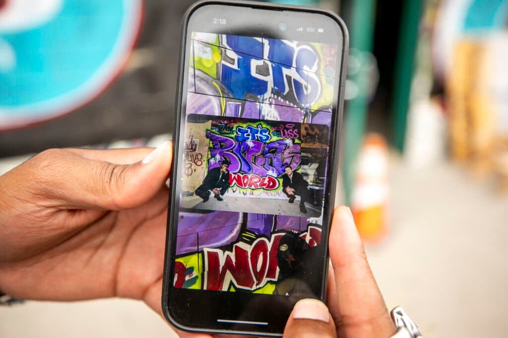 A close-up of hands holding a phone, which is displaying a photo of a mural.