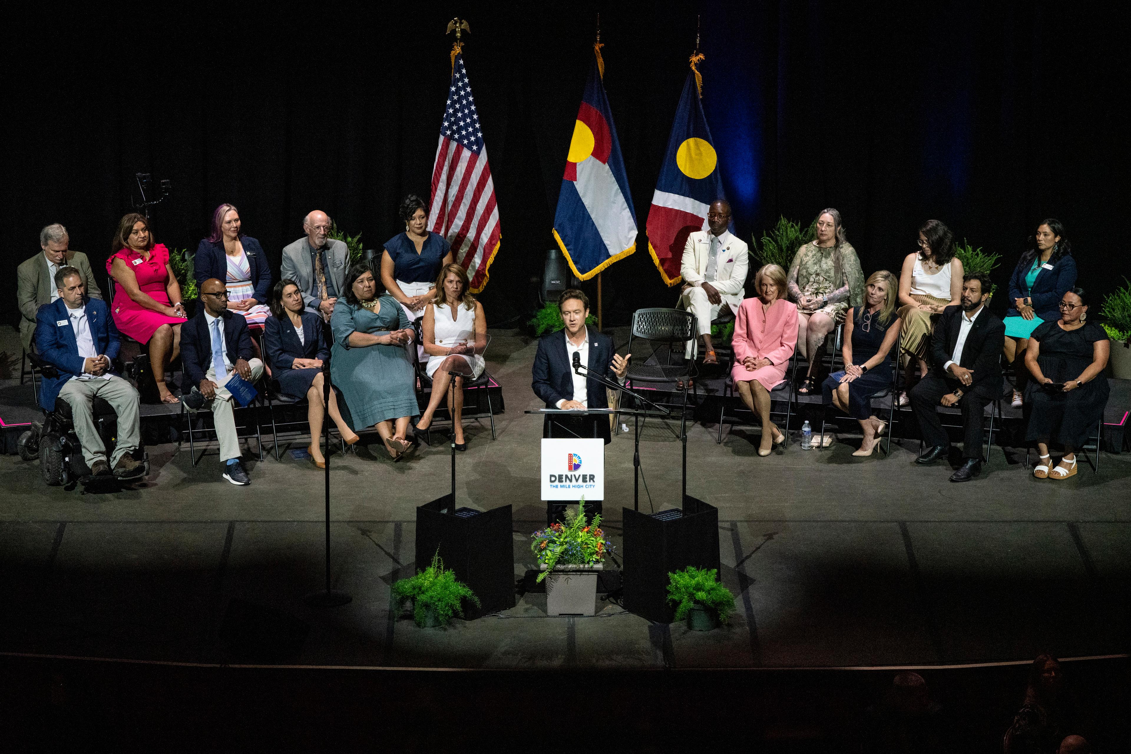 Mike Johnston stands on stage, flanked by other City of Denver officials, as he delivers his State of the City address.