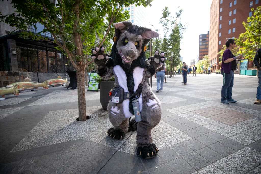 A person in a kind-of scary, full-body rat costume holds up their paws in a pose for the camera.