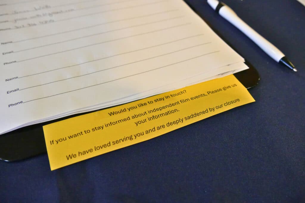 A contact list at the Chez Artiste, soliciting names, emails, and phone numbers of patrons who want to stay in touch. The sign on the sign-up sheet reads, &quot;Would you like to stay in touch? If you want to stay informed about independent film events, please give us your information. We have loved serving you and are deeply saddened by our closure.&quot;