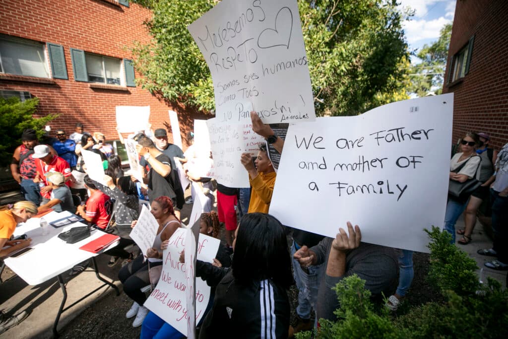 A group of people hold signs; the closest reads &quot;We are father and mother of a family.&quot;