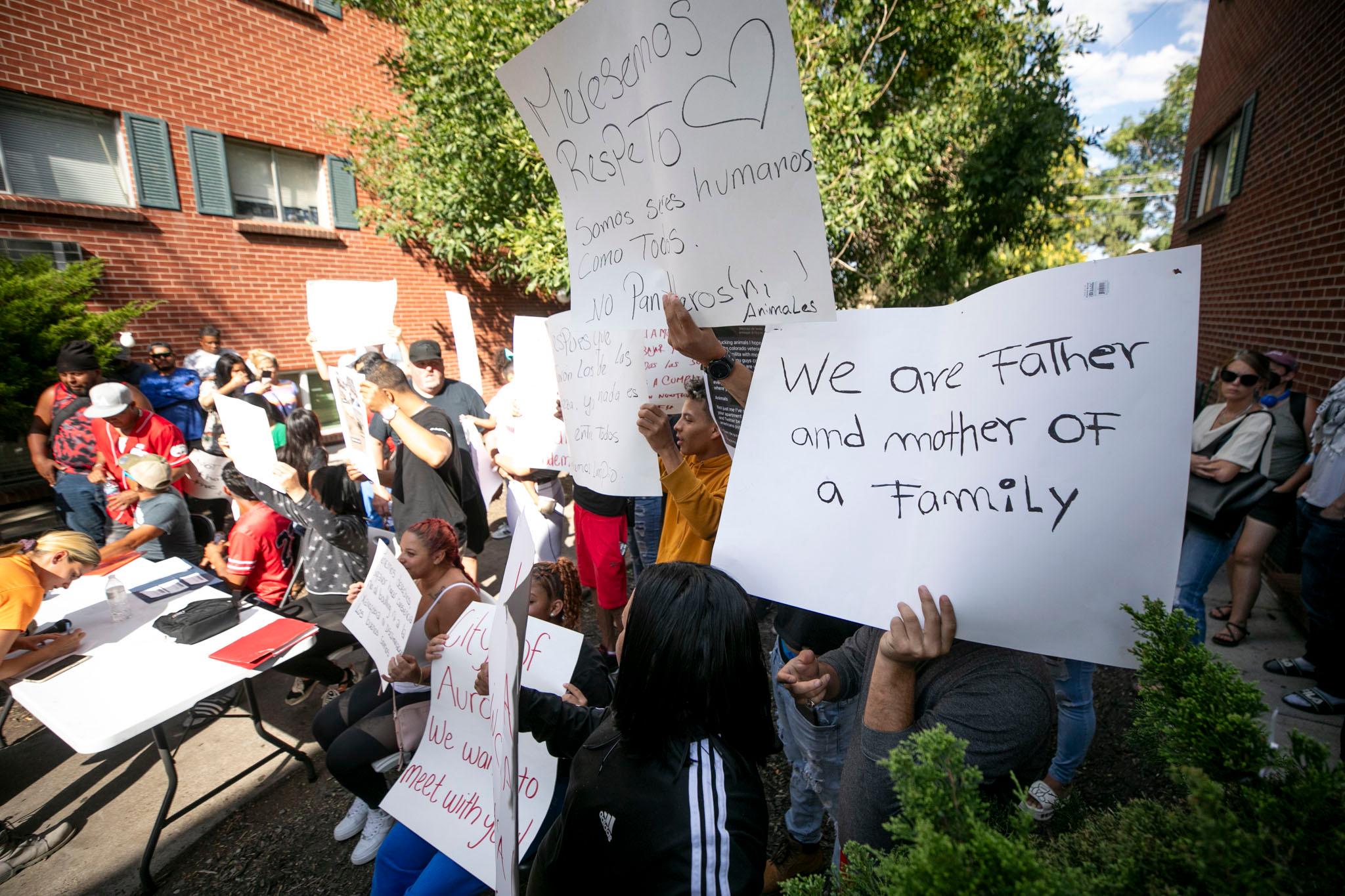 A group of people hold signs; the closest reads "We are father and mother of a family."