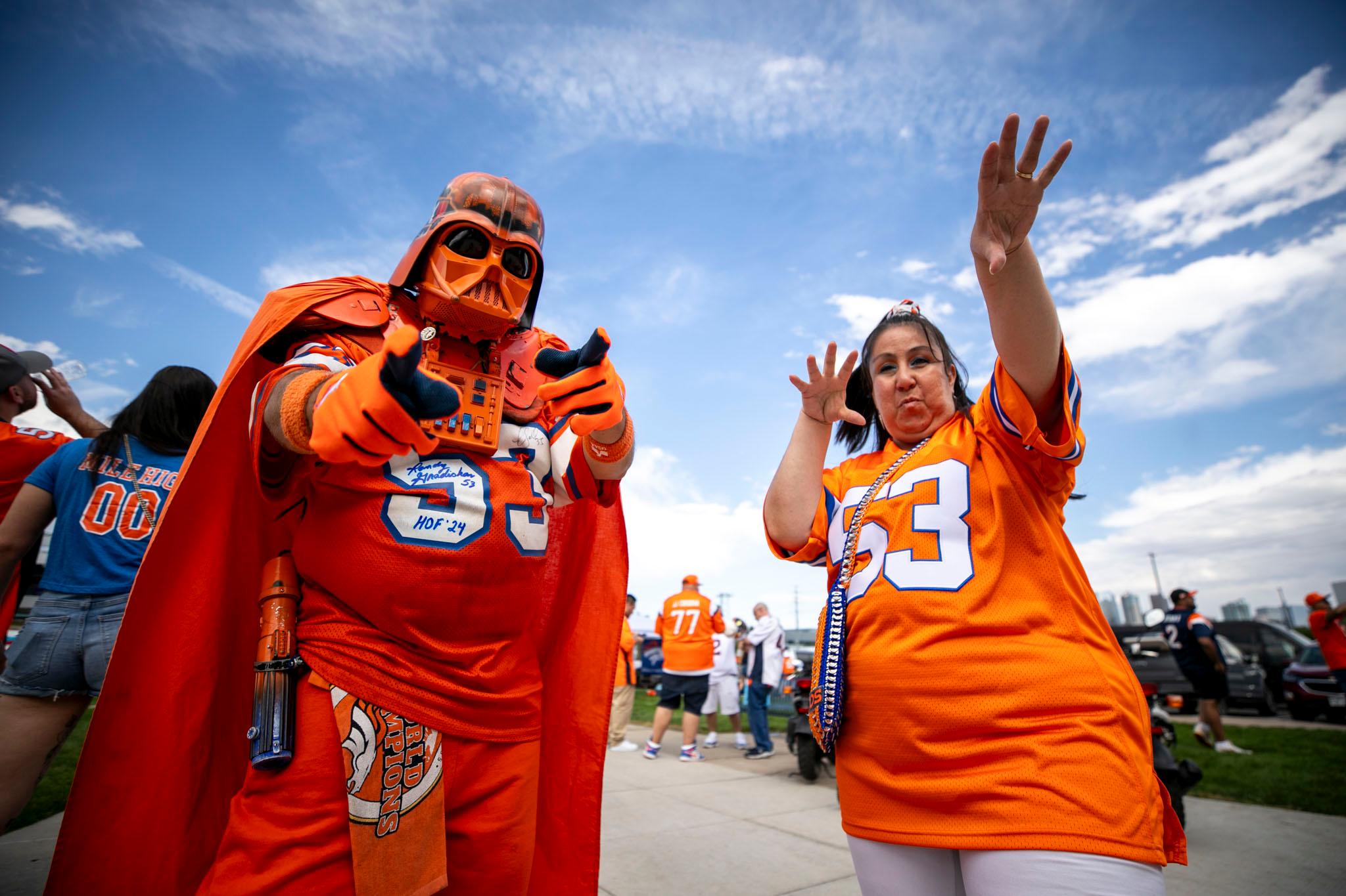 A man in an orange Darth Vader costume and a woman in an orange Broncos jersey point at the camera, as if to say: We rule.