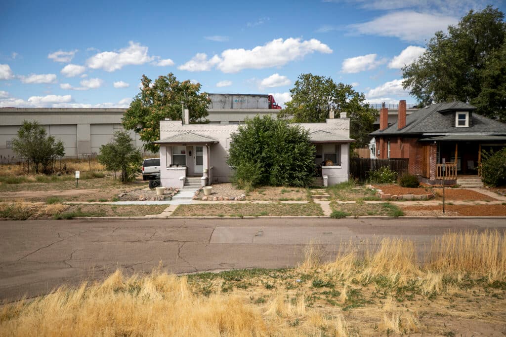 A truck drives across a highway overpass above a grey duplex.