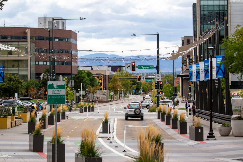 A view down Larimer Street, with Speer Boulevard signs and rope lights partially blocking a view of the mountains beyond.