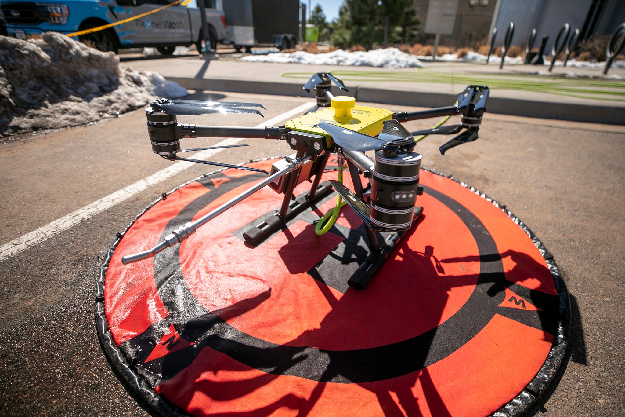 A drone resting on an orange pad on the ground.