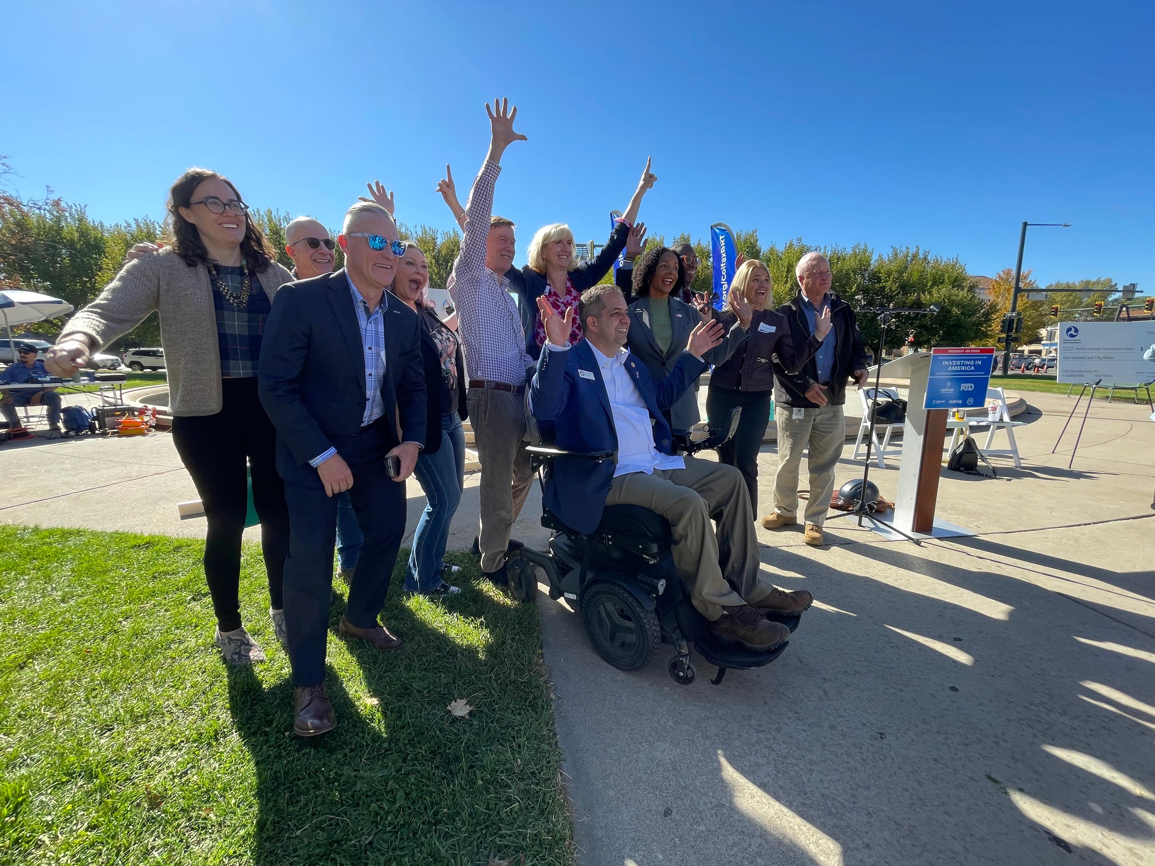Denver City Council members and other dignitaries raise their hands in celebration.