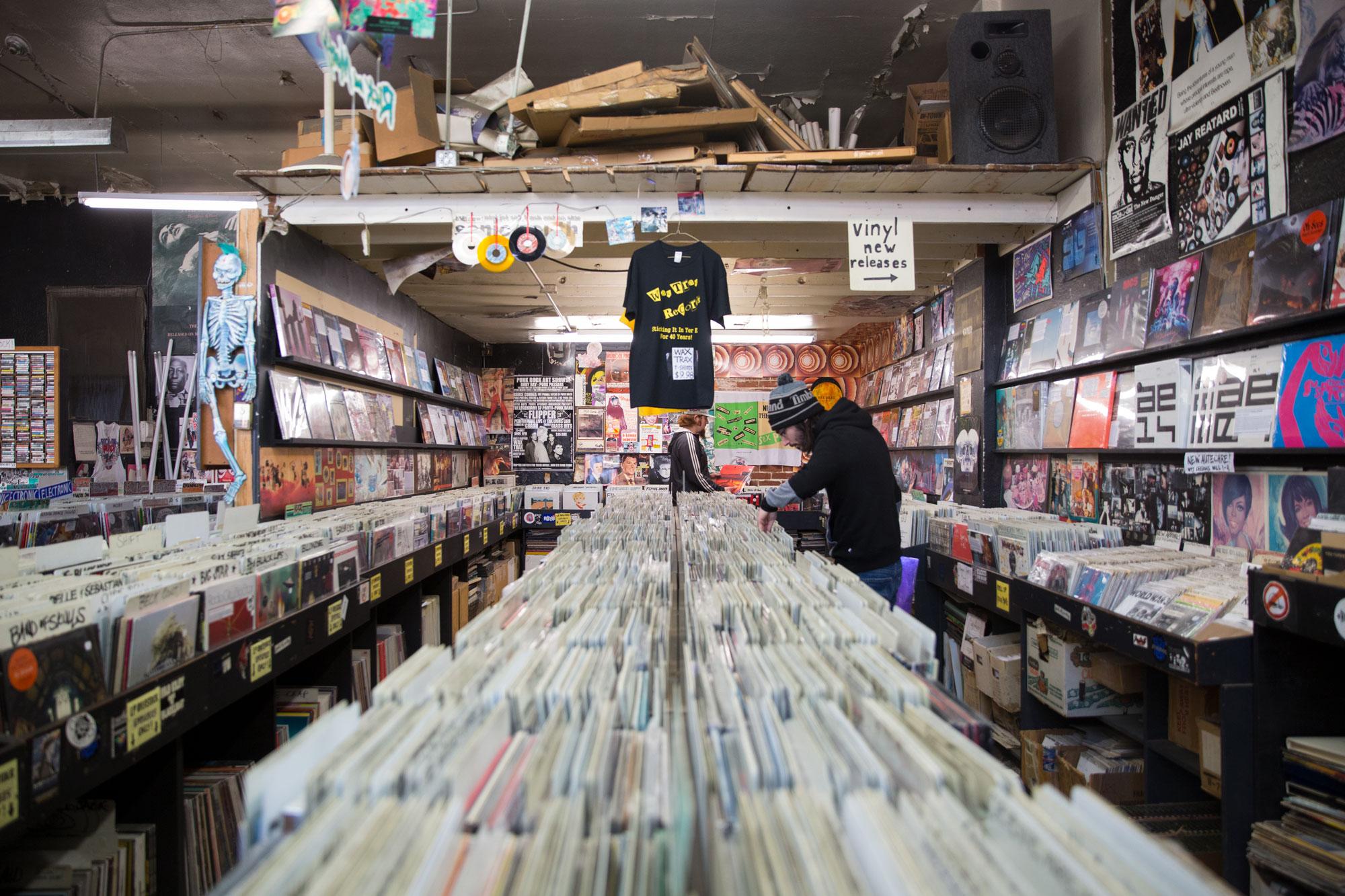 A guy in a beanie and a black hoodie browses through a long line of records at Wax Trax's Capitol Hill location.