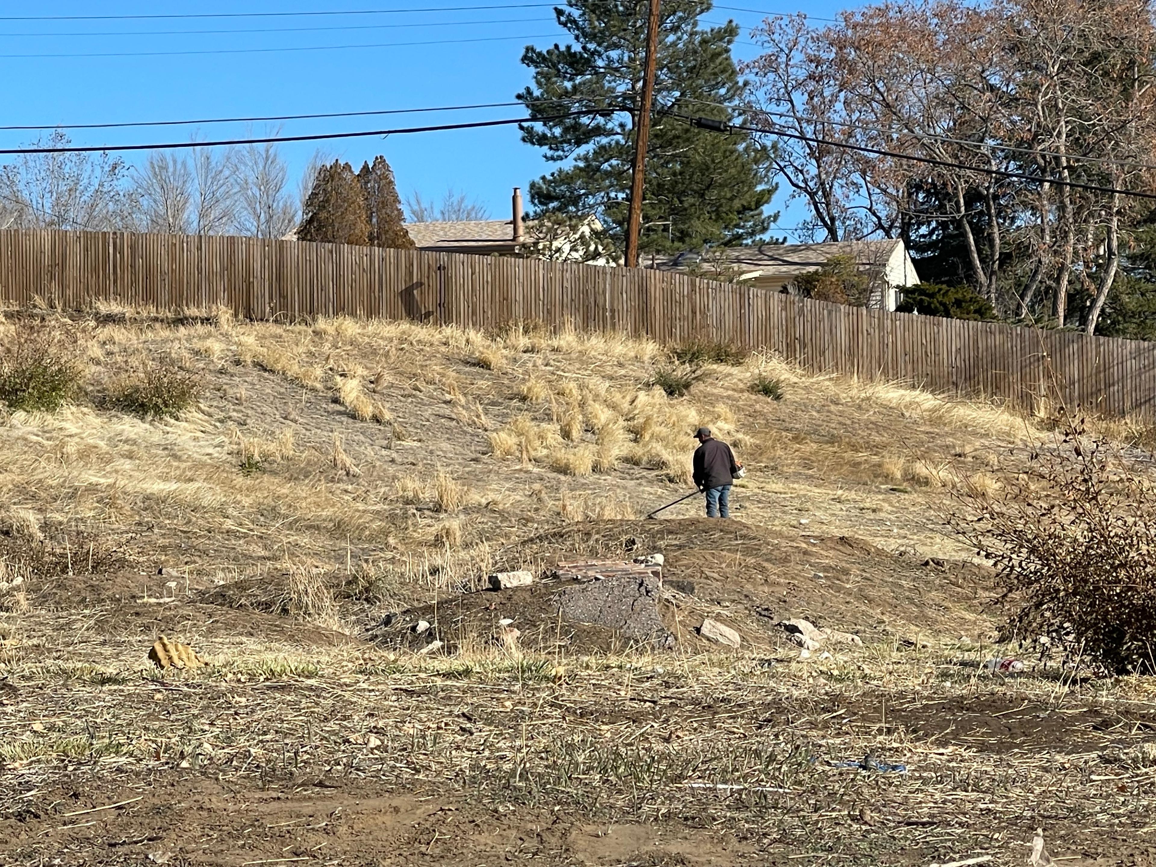 A worker removes weeds from a dried up patch of land.