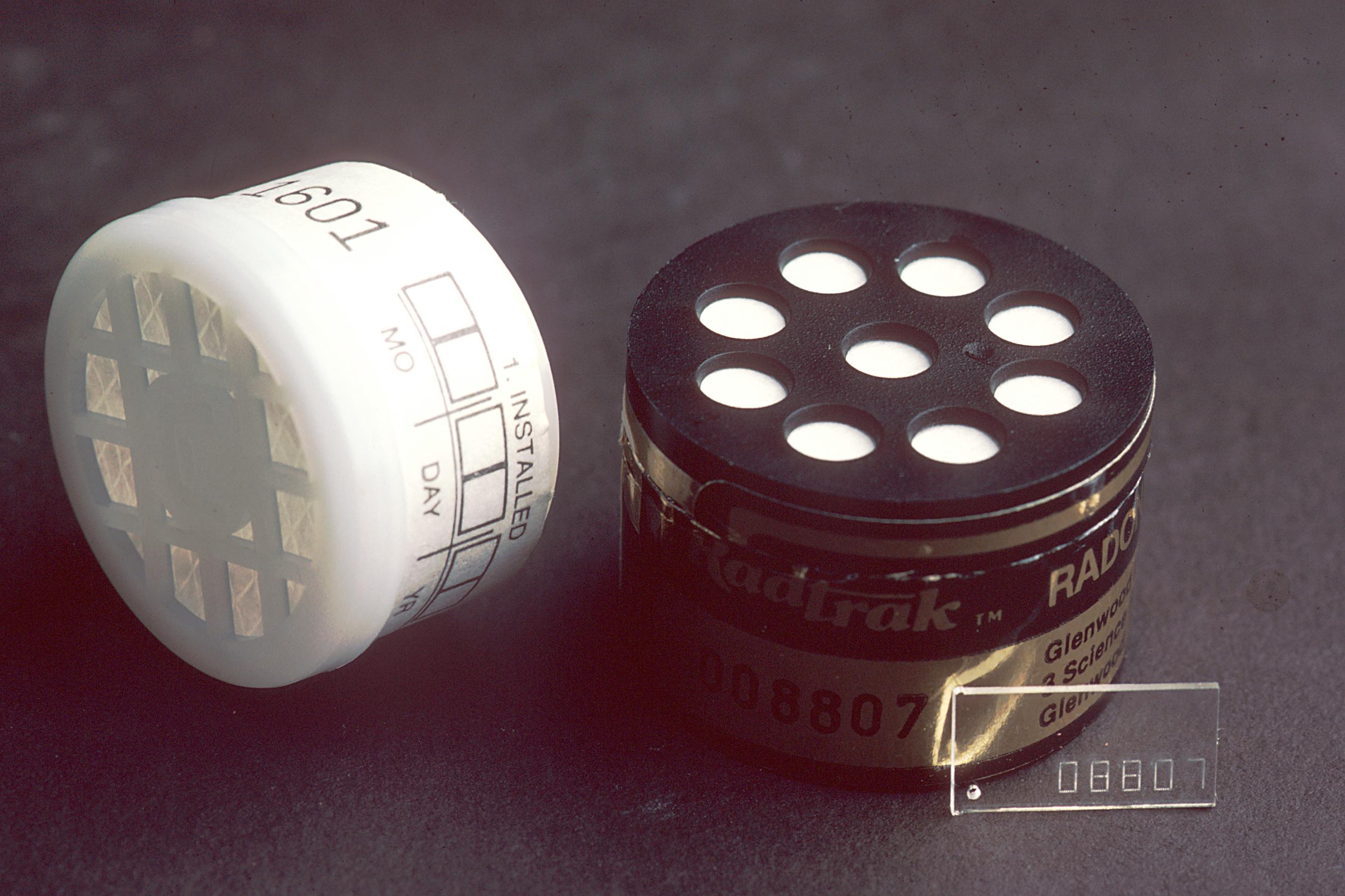 A photo of a radon test kit, which looks like a squat plastic cylinder with holes on the top.