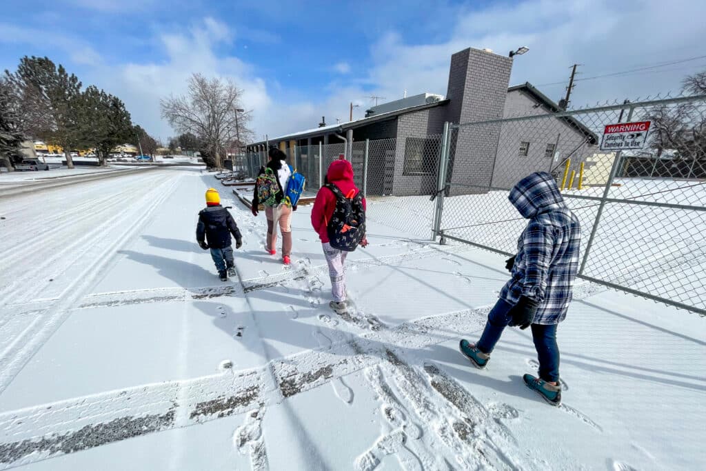A woman walks three kids through the snow to school.