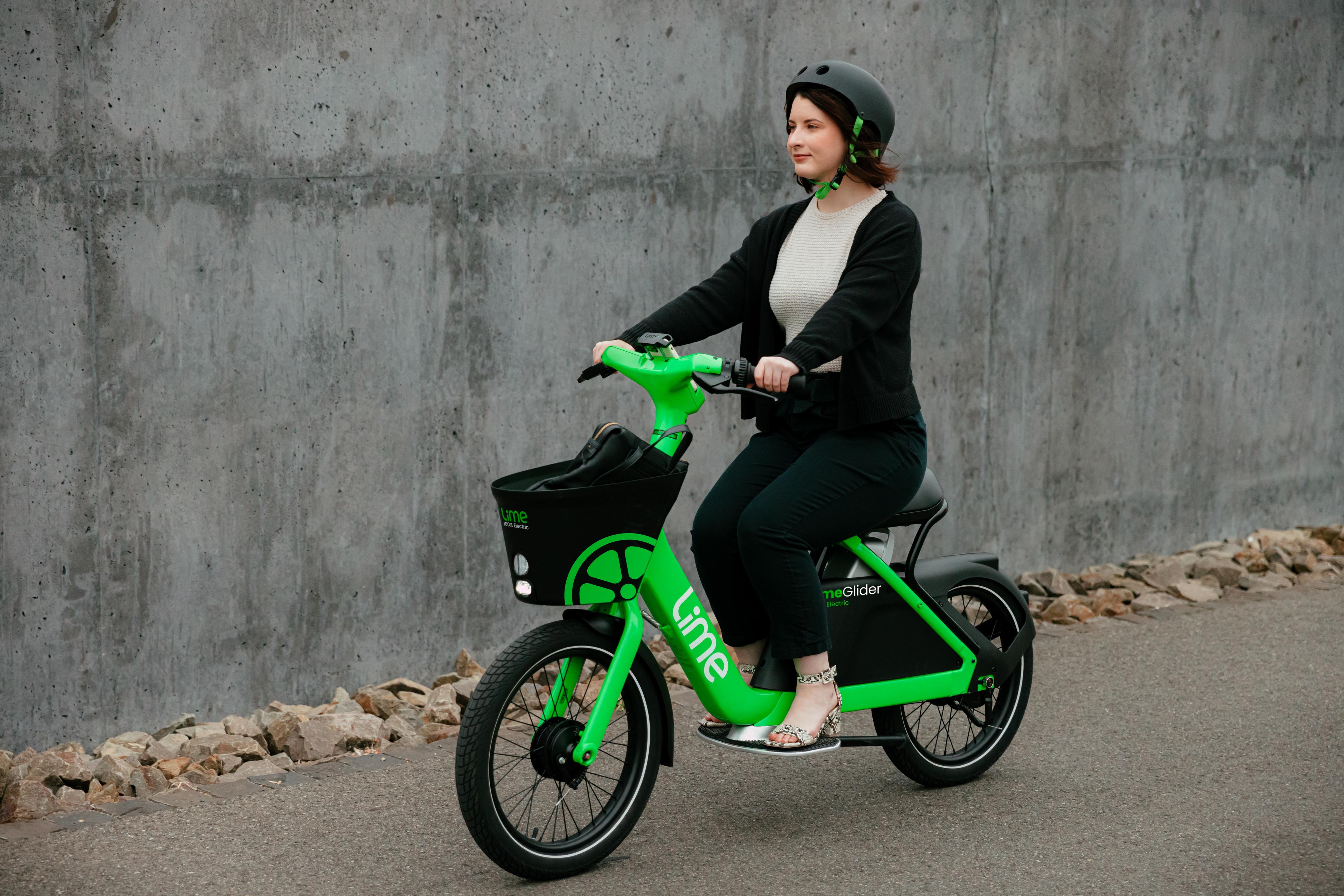 A woman in business attire rides Lime's new scooter-bicycle hybrid.