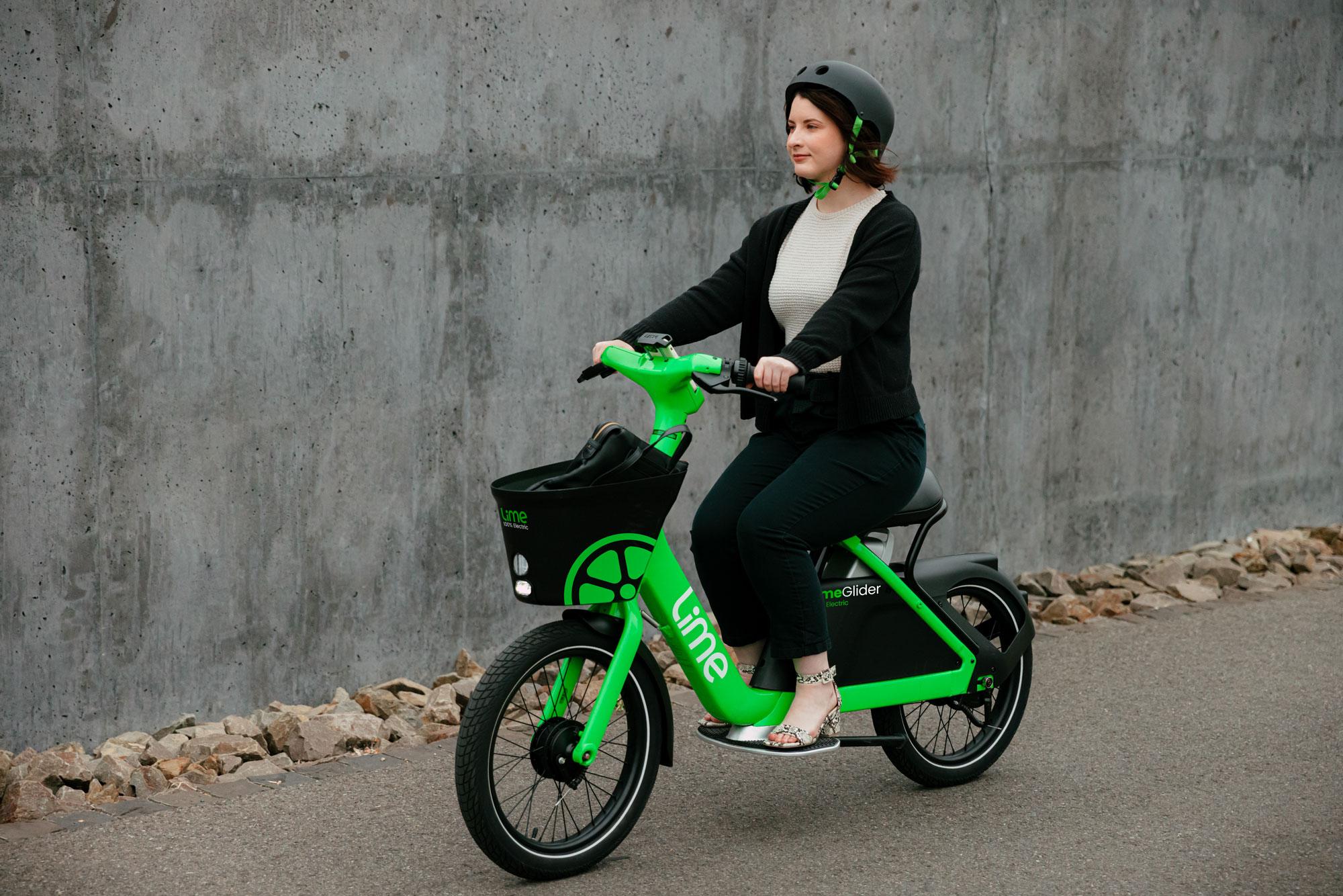A woman in business-casual attire rides Lime's new scooter-bicycle hybrid.