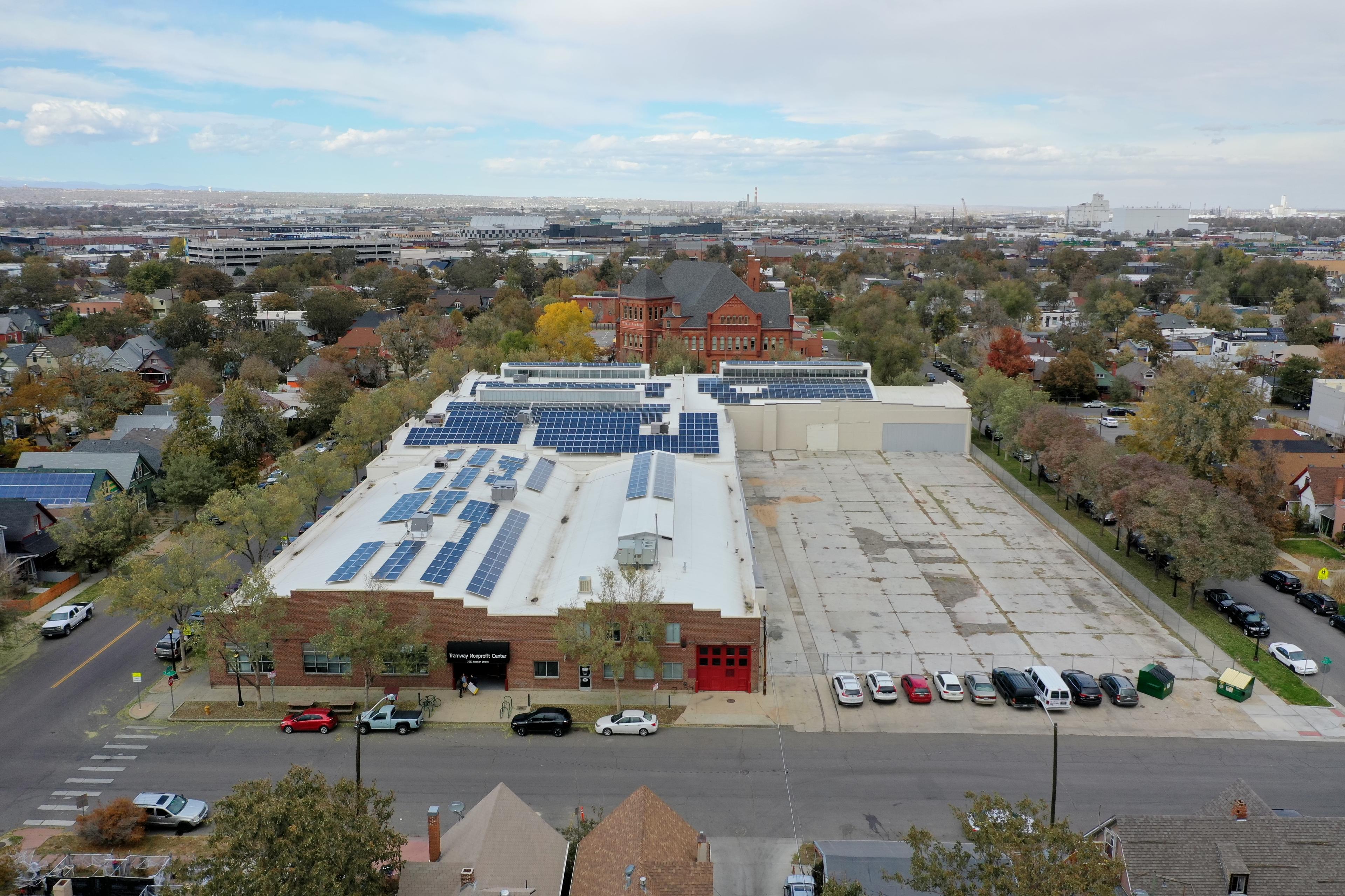 An aerial view of a large property with a brick building on the left and an empty lot on the right.