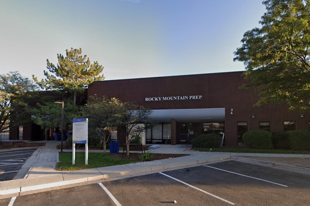 Front of a school with a parking lot and trees