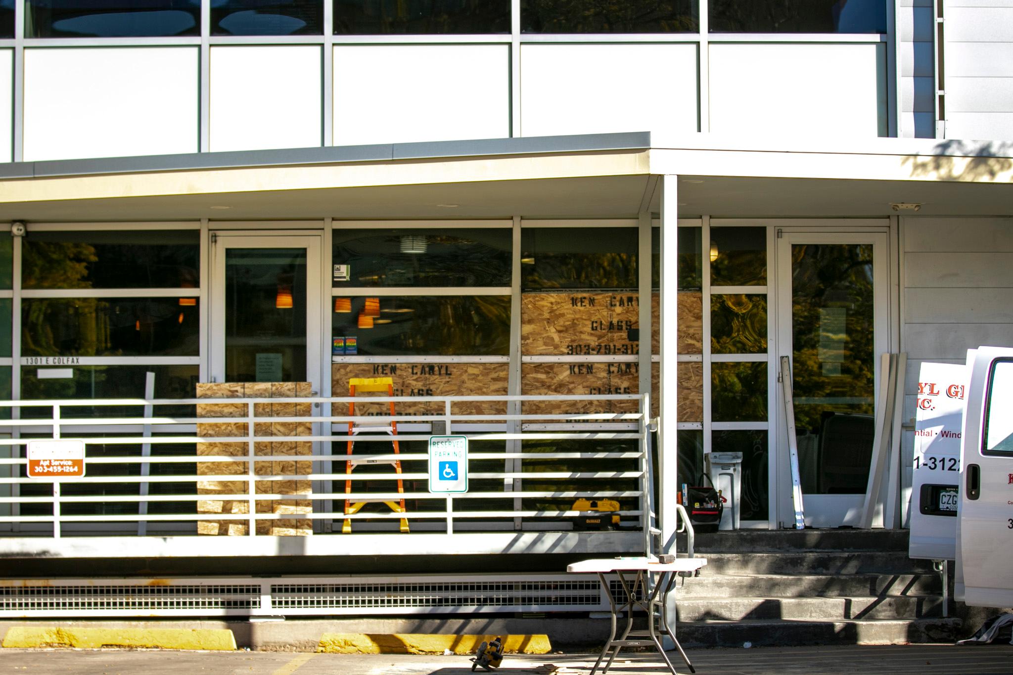 The front of a building has multiple of its windows covered in plywood.