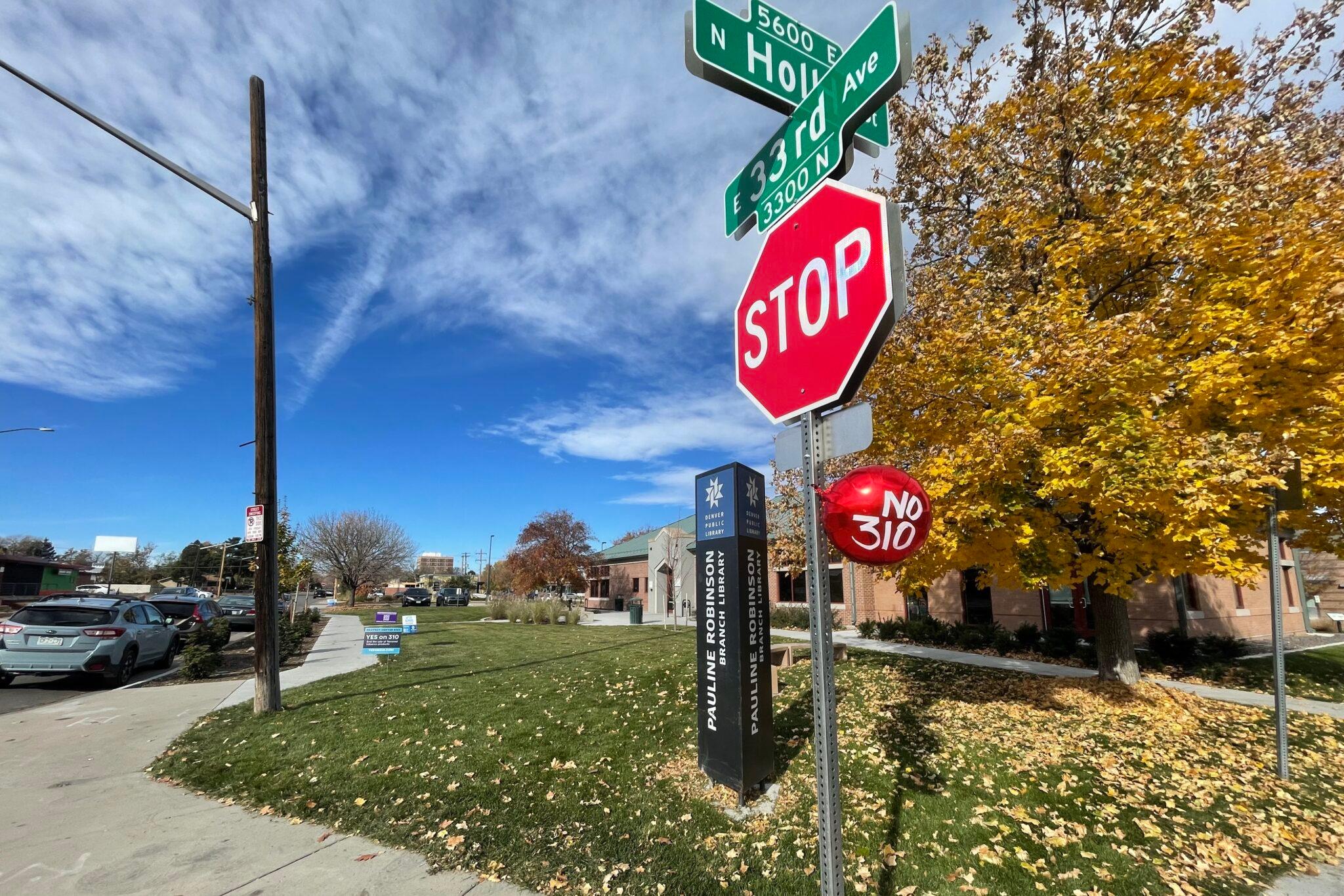 A red balloon with &quot;No on 310&quot; written in white lettering is tied under a stop sign.