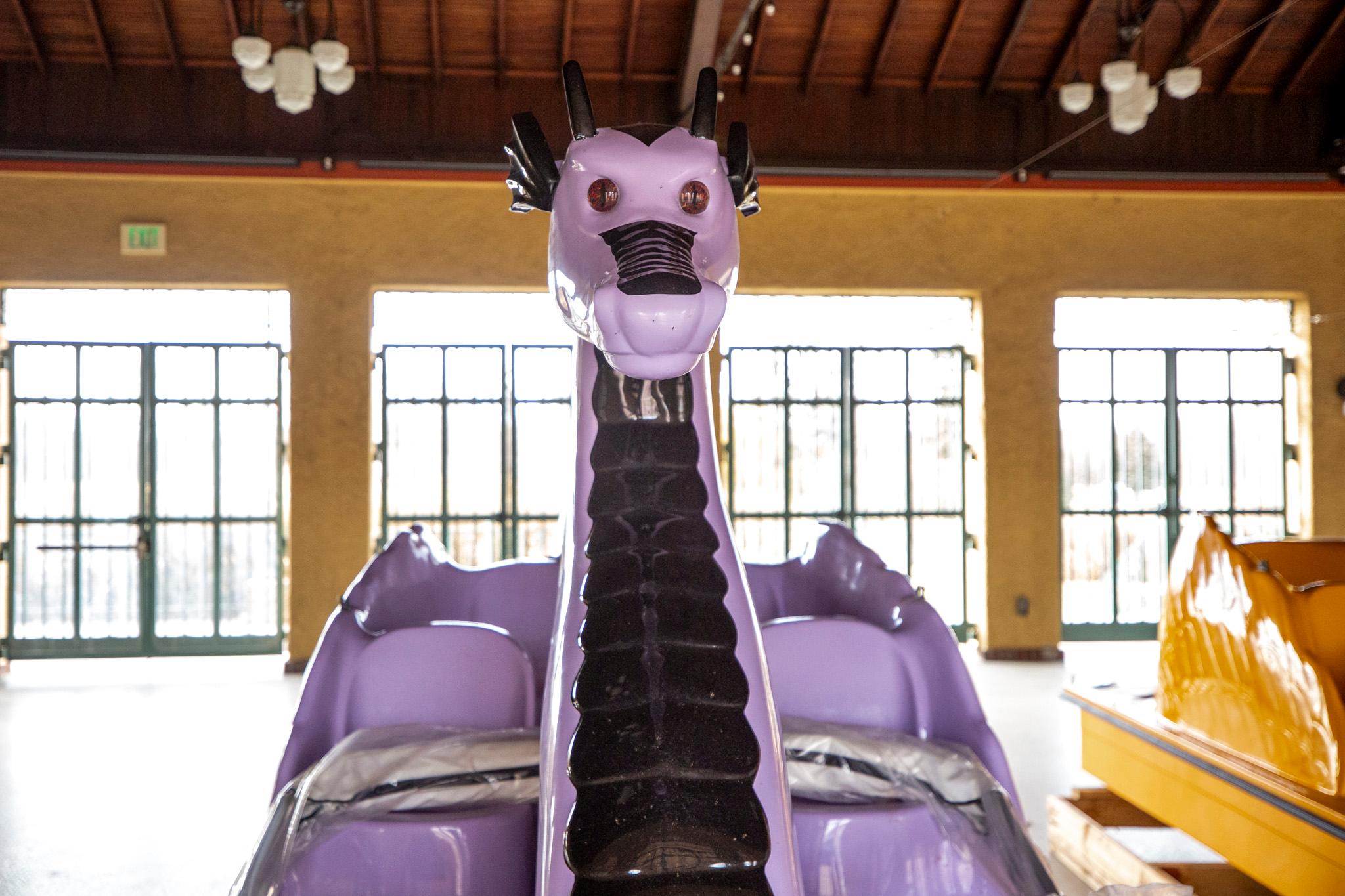A purple dragon head in a bright yellow room. The shiny plastic beneath it reveals its body is actually a boat.