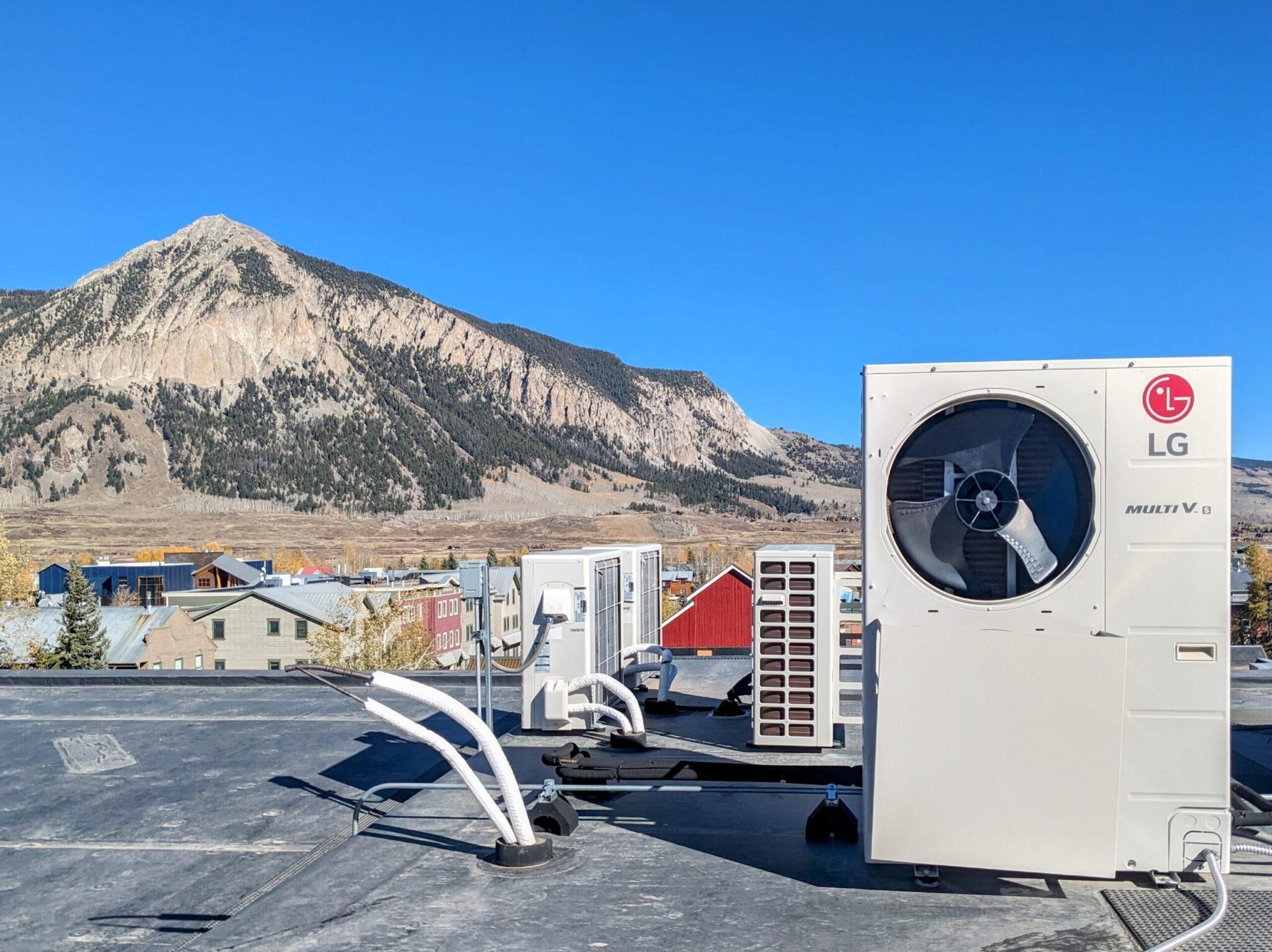 A large piece of machinery on top of a flat grey roof. Mountains sit in the background.