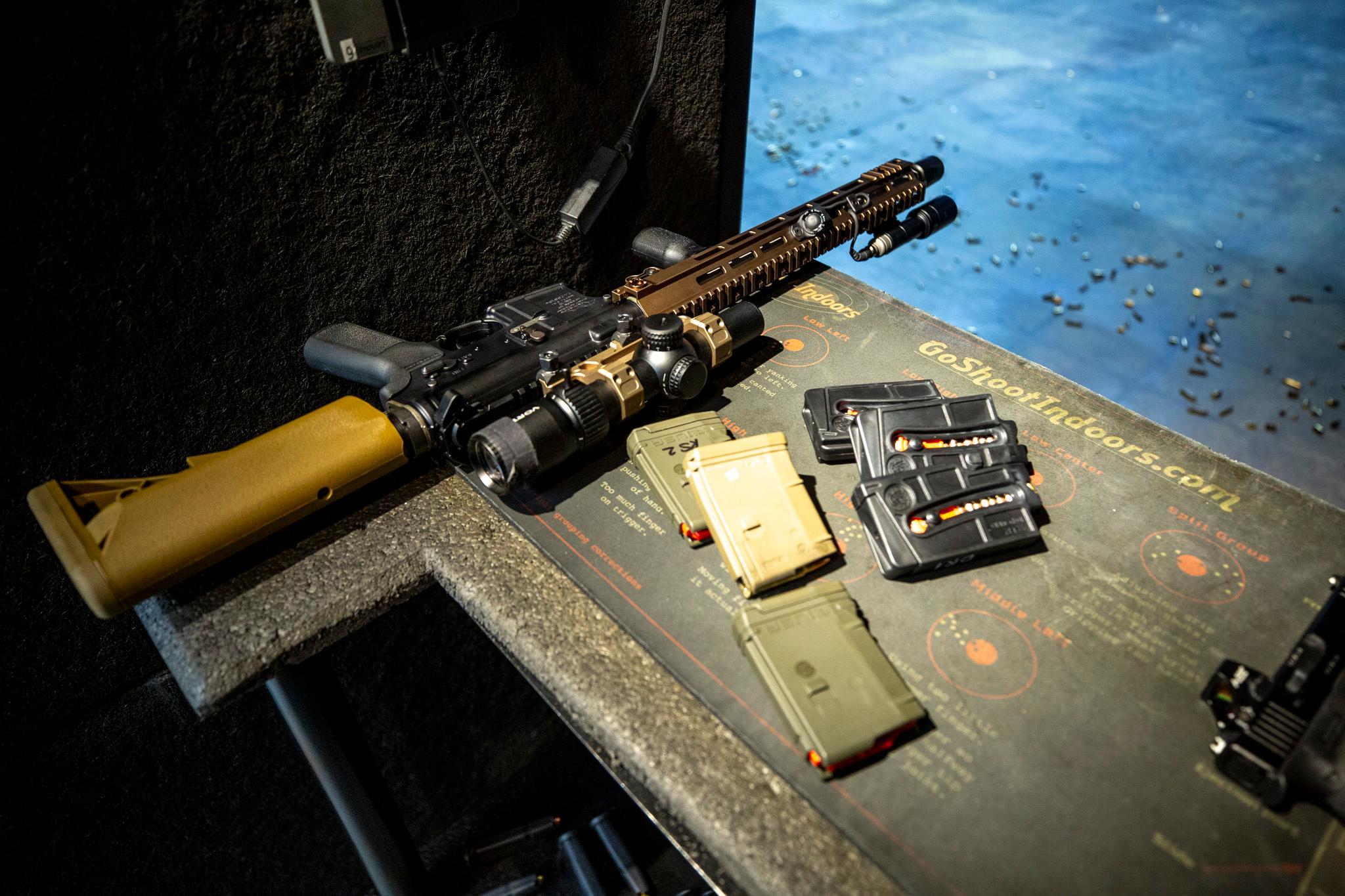 A green and black rifle, topped with a scope, sits on a table surrounded by black and green ammunition clips.