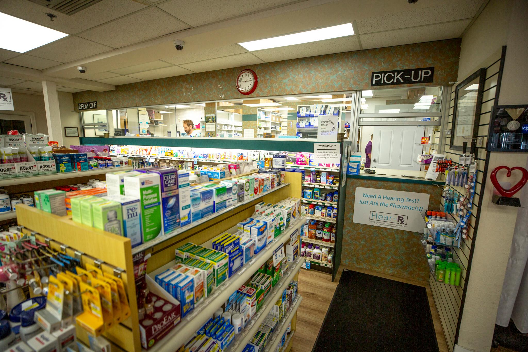 A sign over a window reads "PICK-UP." In the foreground are shelves full of colorful boxes.